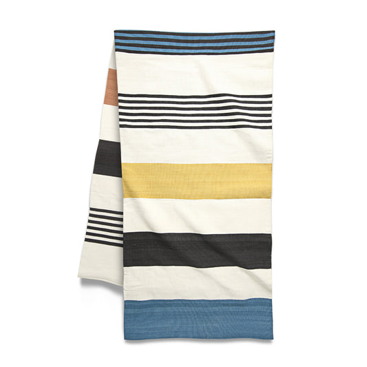 A folded striped cotton blanket in various colors including blue, beige, black, and white.