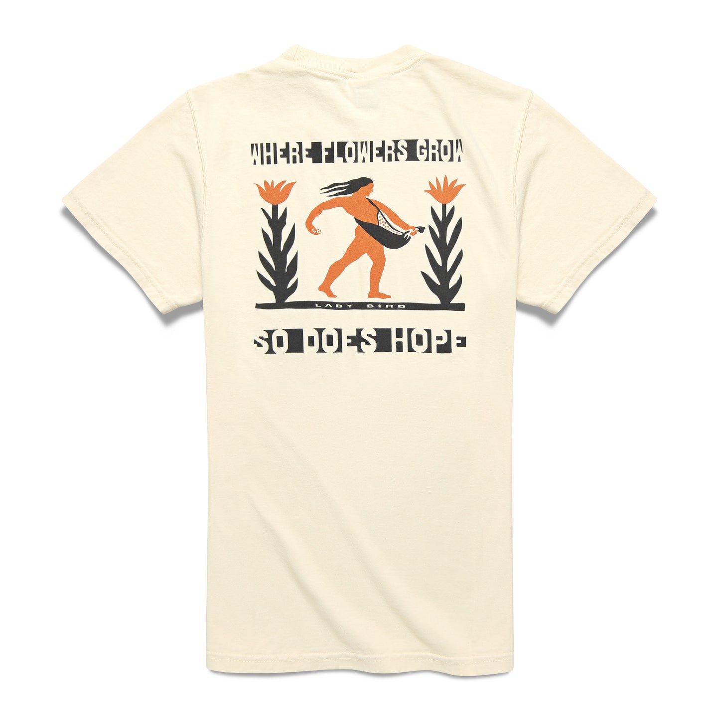 Beige tshirt with black and orange graphic of person carrying seeds with tall flower plant on either side. Text reads 'WHERE FLOWERS GROW SO DOES HOPE'