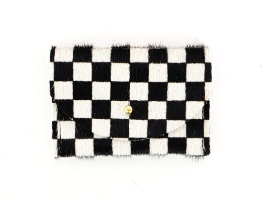Black and white checkered cowhide cardholder with golden colored brass hardware against white background