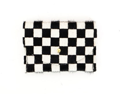 Black and white checkered cowhide cardholder with golden colored brass hardware against white background