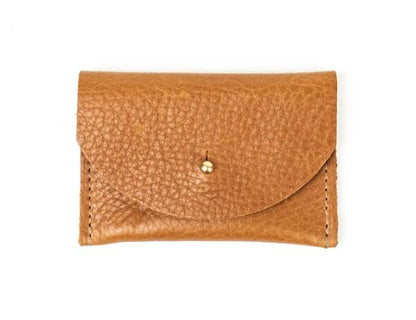 Pebbled leather light brown cardholder with golden colored brass hardware against white background