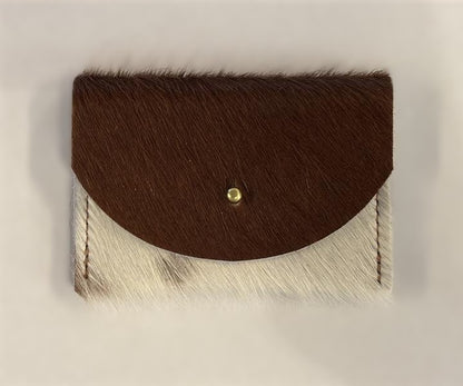 Brown and white cowhide cardholder with golden colored brass hardware against white background