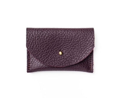 Pebbled leather plum purple cardholder with golden colored brass hardware against white background