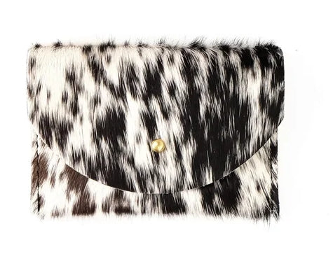 Black and white cowhide cardholder with golden colored brass hardware against white background