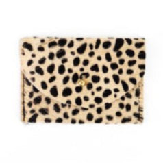 Spotted black on cream cowhide cardholder with golden colored brass hardware against white background